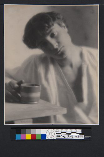 Joven en bata blanca con taza de café, sentado.