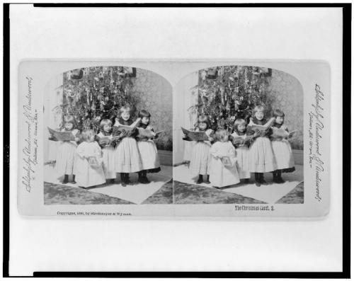 El villancico navideñoCinco niños ante el árbol de Navidad, cantando villancicos de los libros.