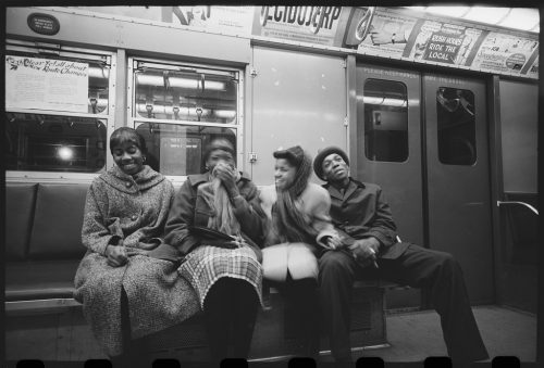 Jóvenes afroamericanos comparten unas risas mientras viajan en metro. 