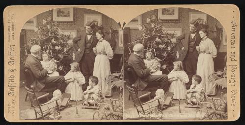 Visita del abuelo la mañana de NavidadFamilia con juguetes delante del árbol de Navidad.